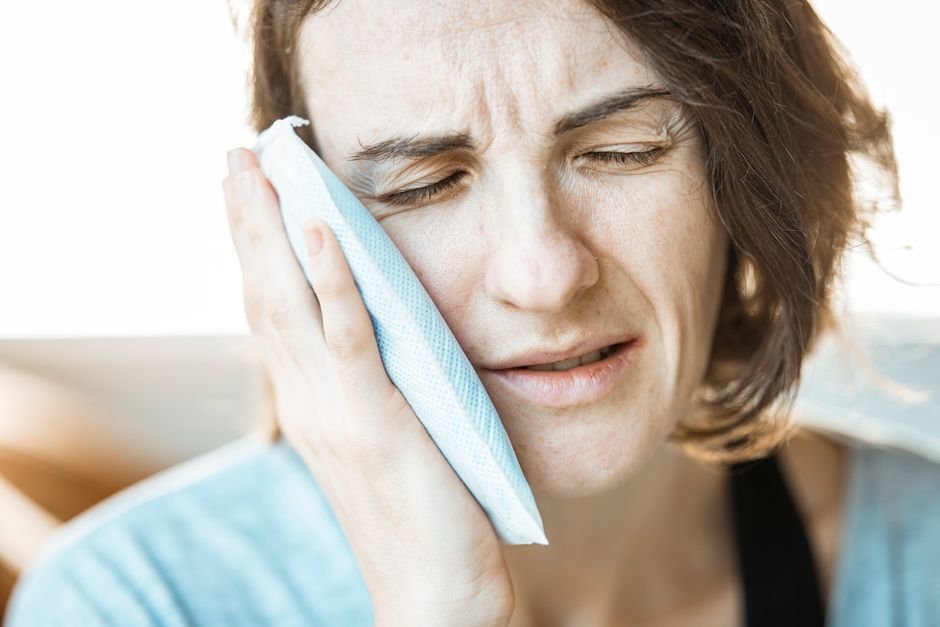 Person experiencing tooth pain and checking dental insurance coverage for emergency care