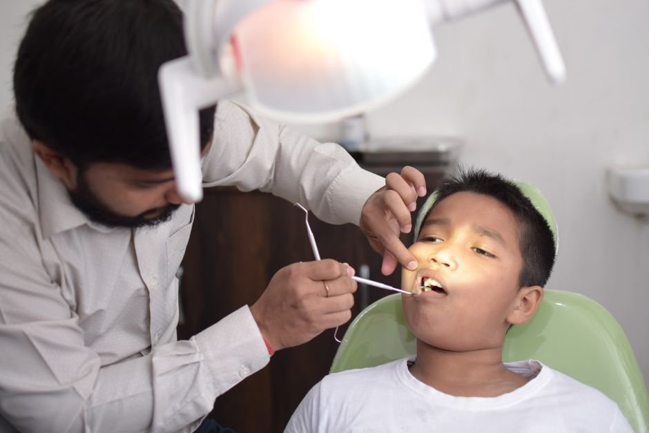 Dentist examining a child's teeth during a routine pediatric dental checkup